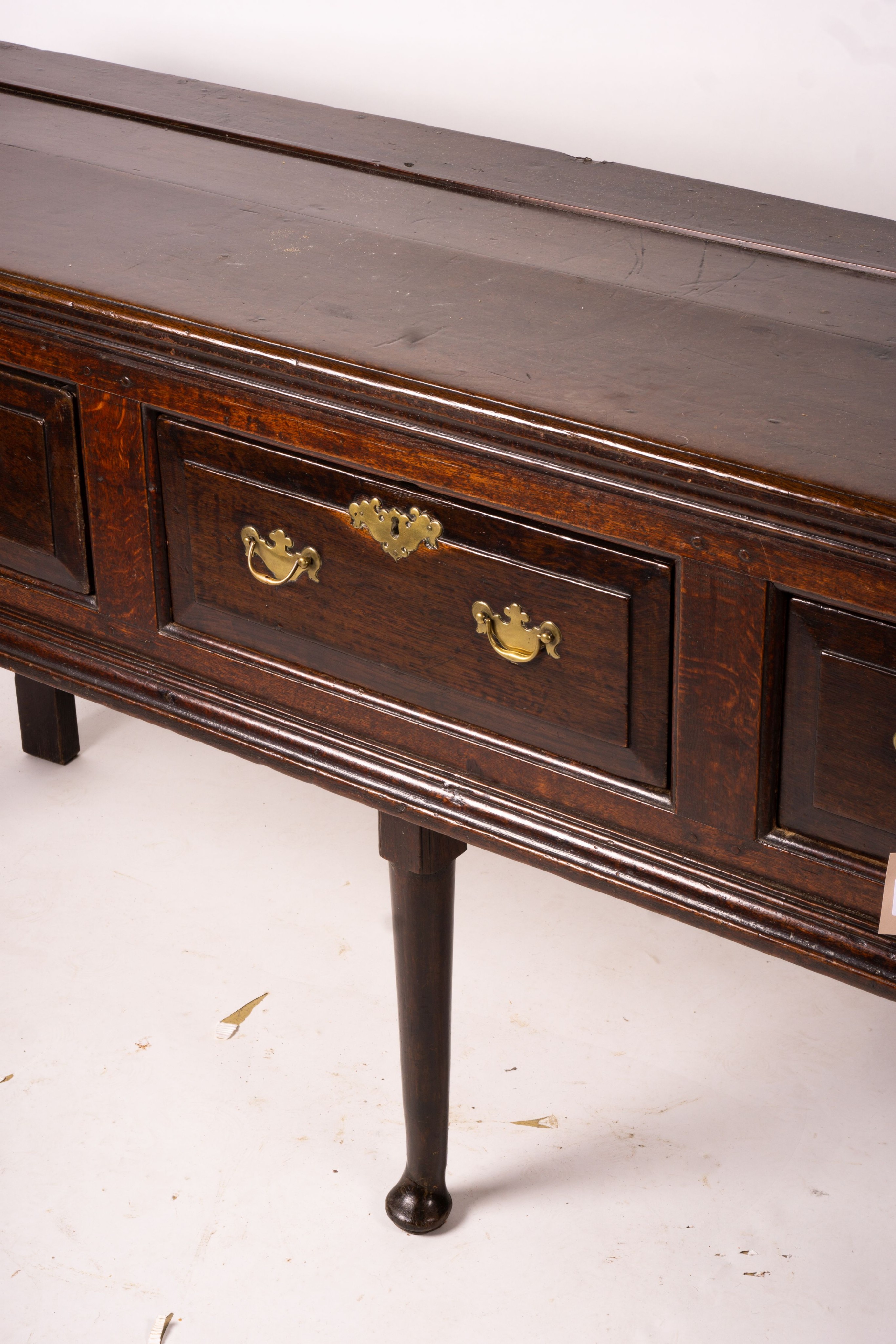 An 18th century oak low dresser on pole turned legs and pad feet, length 198cm, depth 53cm, height 88cm